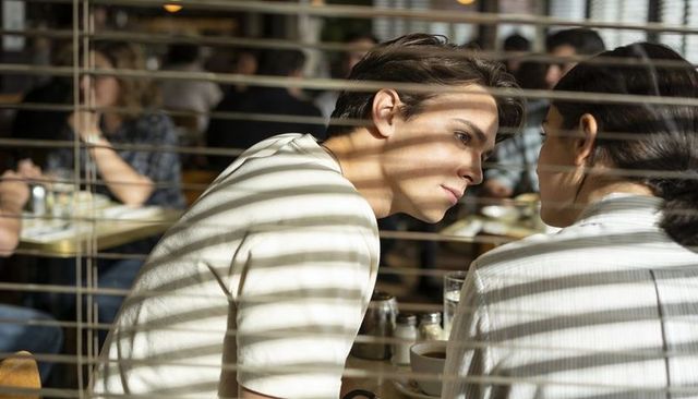 Teen couple leaning forward in cafe with dramatic blind shadows and sunlit mood