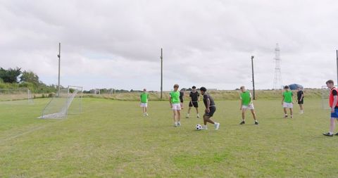 Diverse Teenage Players Dribbling Soccer Ball on Grassy Pitch