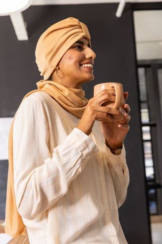 Confident Indian Woman Enjoying Coffee in Modern Office Environment