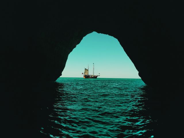 Silhouette of pirate ship seen from inside a sea cave, suggesting mystery and adventure on the open ocean. Suitable for themes of travel, exploration, adventure, and nautical journeys. Ideal for use in travel blogs, adventure articles, marine studies, and tourism advertisements.