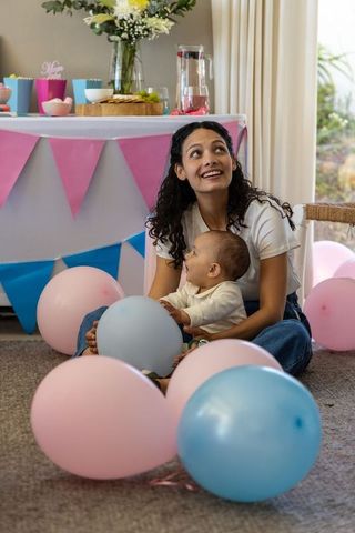 Joyful mother and infant among pastel balloons during celebration