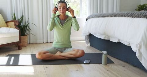 Woman Meditating with Wireless Headphones on Yoga Mat