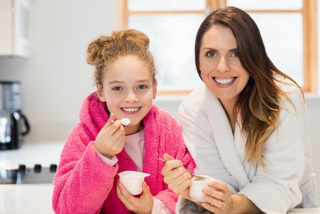 Mother and daughter eating ice cream in kitchen at home