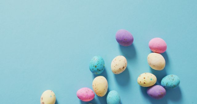 Image of decorated colorful easter eggs on a blue surface. seasonal easter traditional sweet treats.