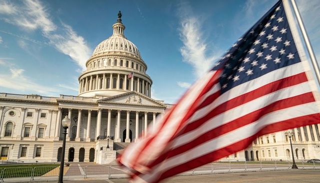 American flag waving across united states capitol plaza with iconic dome and columns