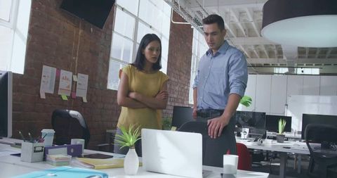 Colleagues reviewing laptop in bright loft office collaborating on project planning session