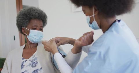 Caregiver Applying Adhesive Bandage to Senior Woman Arm During Home Health Visit