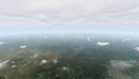 High-altitude farmland grid showing patchwork fields under low overcast sky