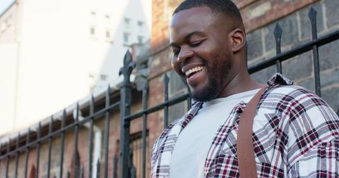 Young african american man smiling outdoors wearing plaid shirt urban lifestyle portrait