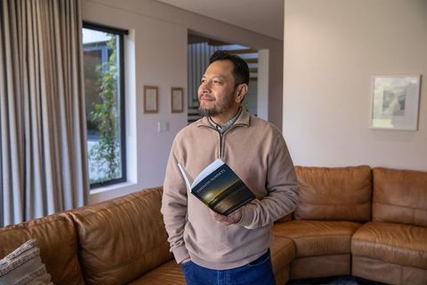Middle-aged asian man reading book in cozy modern living room | relaxed home lifestyle