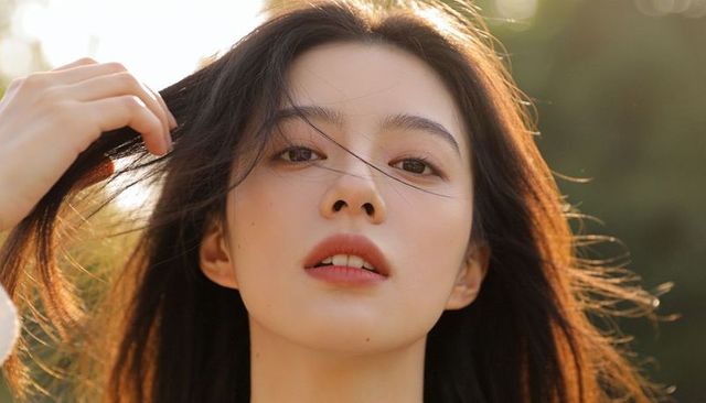 Sunlit asian woman tucking hair closeup portrait with golden hour rimlight natural makeup bokeh