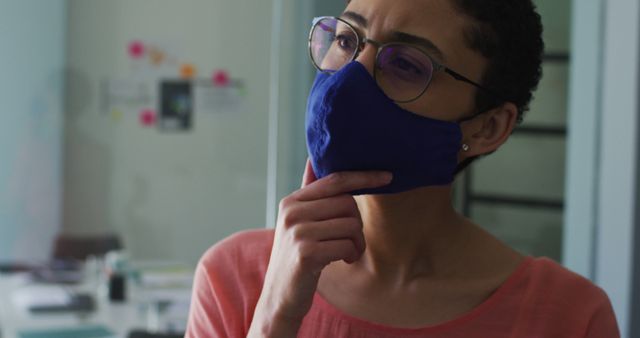 Thoughtful Professional Woman Wearing Mask Looking Aside in Office - Download Free Stock Images Pikwizard.com