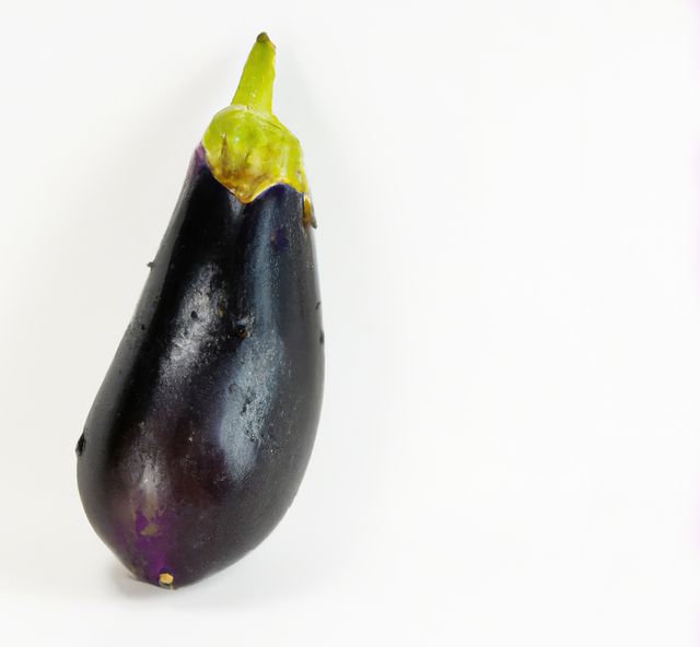 This image presents a single fresh eggplant on a white background. The focus is on the shiny, deep purple color and healthy condition of the eggplant. The image can be used for culinary websites, health and nutrition blogs, recipes, grocery store promotions, or educational material regarding vegetables.