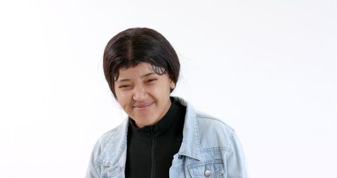 Confident woman smiling in denim jacket on white background