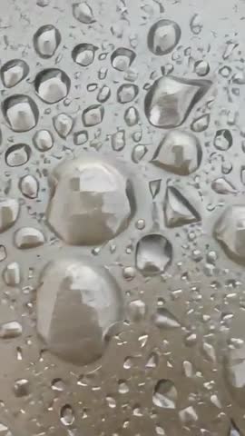 Shifting camera revealing water droplets on glass with window reflections | Vertical macro video