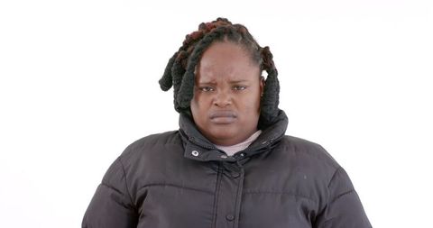 Serious woman in winter coat against white background