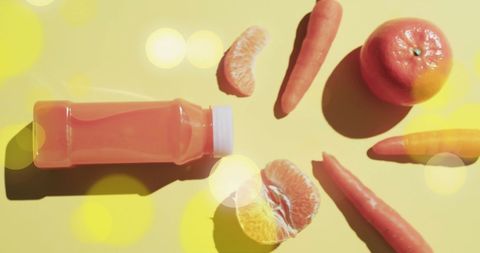 Refreshing Juice Bottle with Carrots and Oranges on Vibrant Yellow