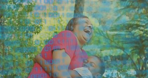 Laughing mother holding daughter in garden with binary code overlay
