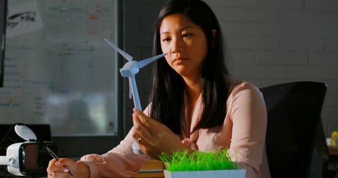Businesswoman Analyzing Wind Turbine Model at Work Desk
