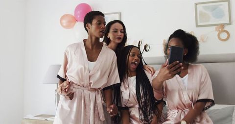 Diverse Group of Friends Taking Festive Selfie in Pink Robes