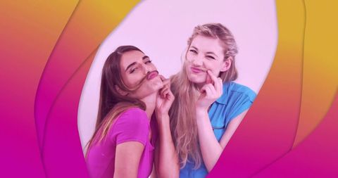 Playful women making hair mustaches, laughing together against vibrant pink blue gradient