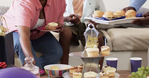 African american family celebrating birthday with cupcake tower and sliders in living room