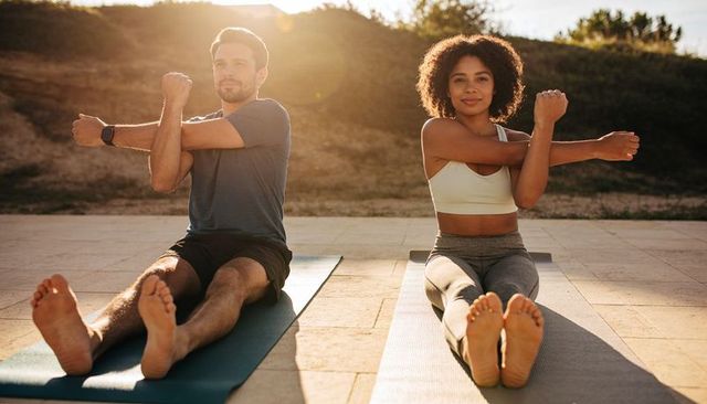 Couple stretching on mats at golden hour, outdoor patio workout, partner fitness training