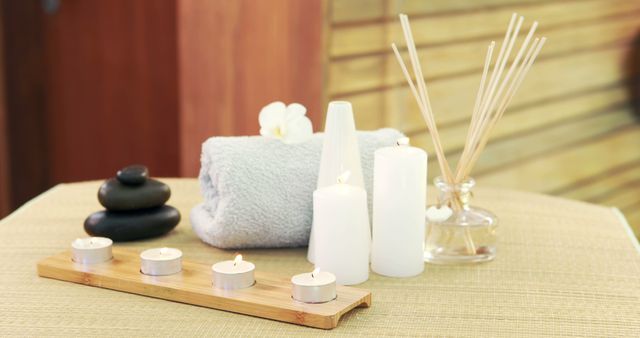 A serene spa setting features candles, aromatic sticks, a towel, and smooth stones, with copy space. It evokes a sense of relaxation and tranquility, often associated with wellness and self-care.