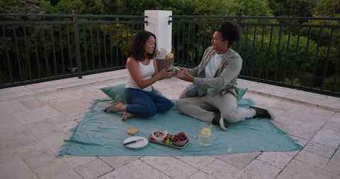 Couple Sharing Picnic on Rooftop Terrace with Young Couple Romantic Scene