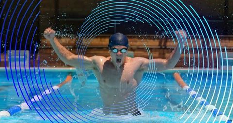 Competitive male swimmer bursting through water in lane, raising arms and splashing with intensity
