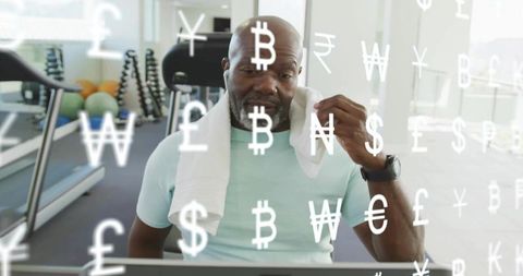Mature man checking digital finance dashboard at gym with floating currency symbols