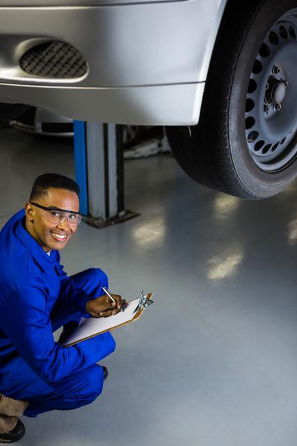 Portrait of happy mechanic preparing a check list at repair garage