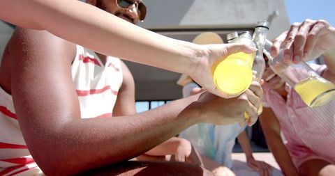 Friends Celebrating with Drinks Outdoors on Sunny Day