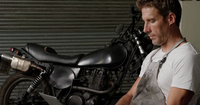 Mechanic Working on Laptop near Motorcycle in Garage Workshop - Download Free Stock Images Pikwizard.com