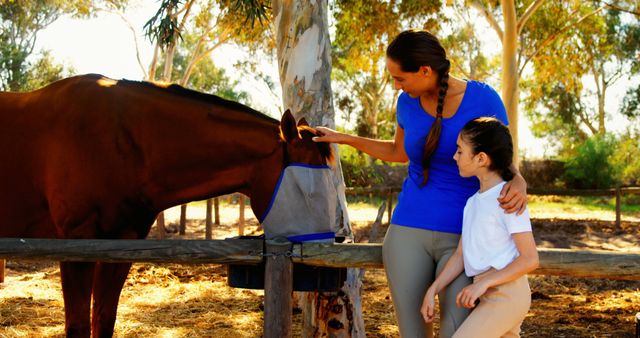 This image depicts a heartwarming moment of a mother and daughter bonding while grooming a horse. Ideal for depicting family activities, equestrian experiences, or summer outdoor adventures. Can be used in articles, blogs, and advertisements focused on family, animal care, or outdoor recreational activities.
