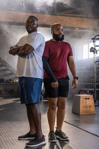 African men standing back-to-back in gym demonstrating teamwork and training focus