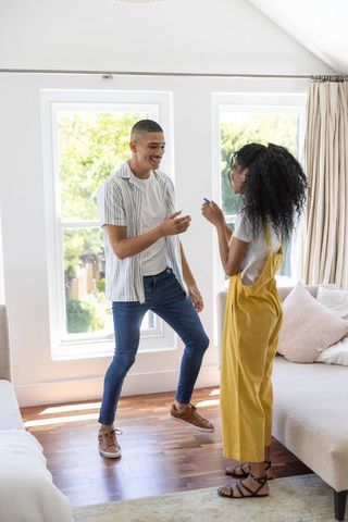 Playful young couple smiling, interacting in sunlit living room during casual home moment