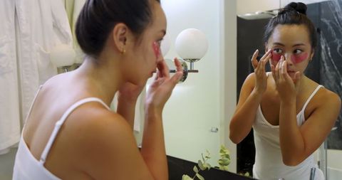 asian woman wearing under-eye gel patches in bathroom mirror - Download Free Stock Images Pikwizard.com