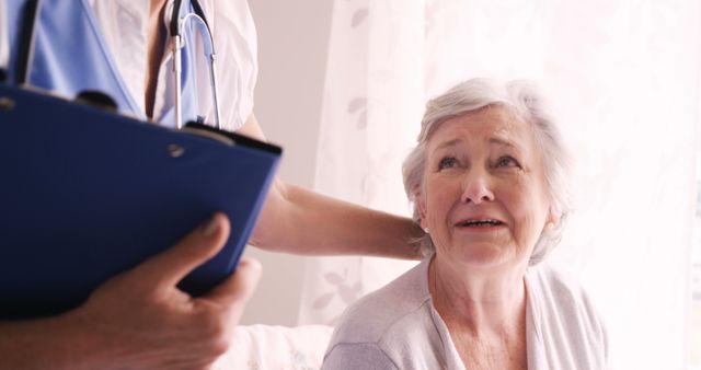 Healthcare professional holding a clipboard comforting an elderly woman, suggesting compassion and care in a medical setting. Useful for depicting senior care, patient support, medical consultation, healthcare services, and doctor-patient relationships.