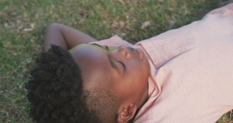 Serene african american boy relaxing outdoors on grass