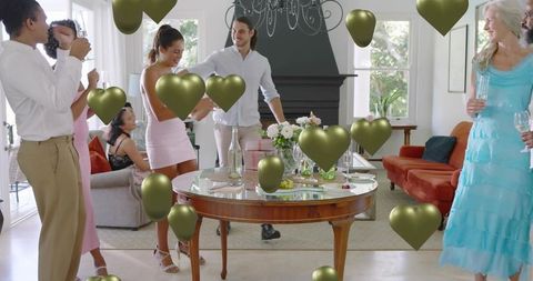 Semiformal House Party Celebrating Around Table with Gold Heart Balloons and Floral Centerpiece