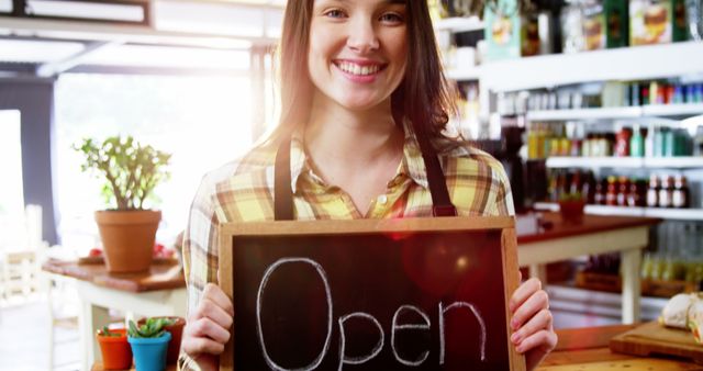Portrait of smiling waitress showing chalkboard with open sign in cafe 4k