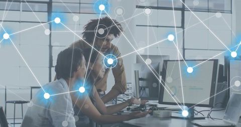 Team collaborating on data dashboards with glowing network overlay in modern workspace