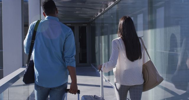 Image of back of diverse man and woman walking with suitcases. business professionals and working in office concept.