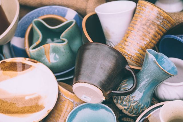 Various handcrafted ceramic pottery pieces with unique designs and shapes, showcasing bowls, mugs, vases, and other small dishes. Perfect for highlighting traditional pottery, artisanal craftsmanship, or colorful home decor. Useful in blogs about pottery making, handmade goods, or home decor inspirations.