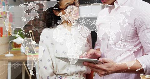 Collaborating on tablet with world map overlay in modern office team brainstorming session