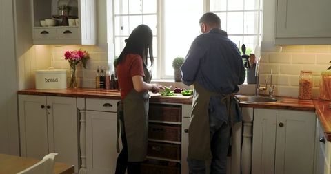 Asian couple preparing colorful bell peppers together in cozy farmhouse kitchen