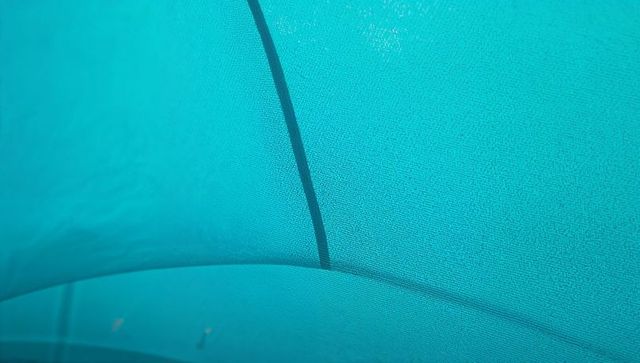 Teal tent canopy showing curved seams and internal rib detail, textured fabric closeup