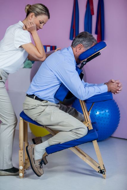 This image shows a physiotherapist providing a back massage to an elderly patient in a clinic. It can be used for articles or advertisements related to healthcare, physical therapy, senior care, wellness programs, and medical treatments. It highlights professional care and the importance of physical therapy in maintaining health and mobility.