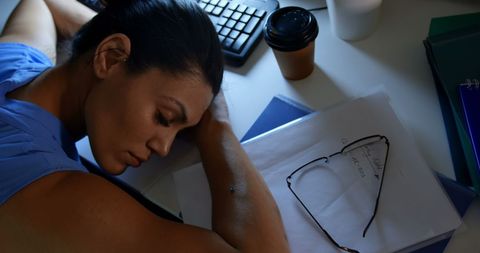 Exhausted businesswoman sleeping at office desk at night